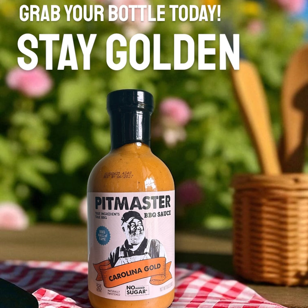 True Made Foods Carolina Gold Pitmaster BBQ Sauce bottle on a picnic cloth with green plants in the background.