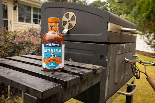 True Made Foods’ Kansas City BBQ sauce on a grill in a backyard.