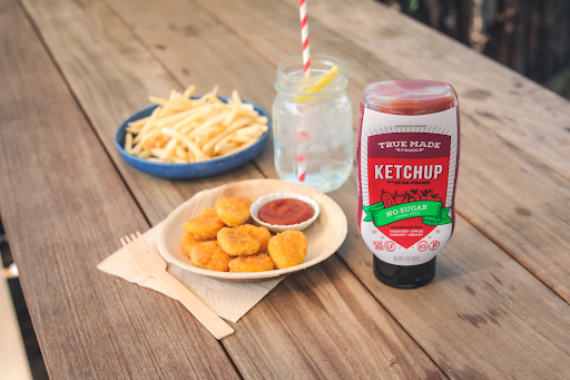 Chicken nuggets and fries served with True Made Foods no-sugar ketchup and lemonade, promoting a low-sugar meal option.