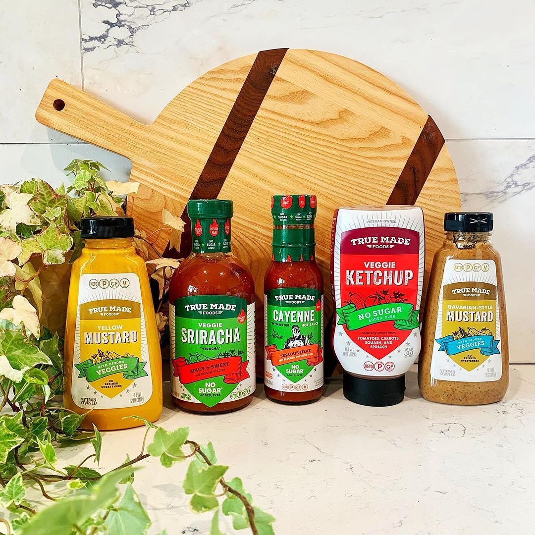 True Made Foods sugar-free condiments lineup featuring three mustards, veggie ketchup, and cayenne hot sauces.