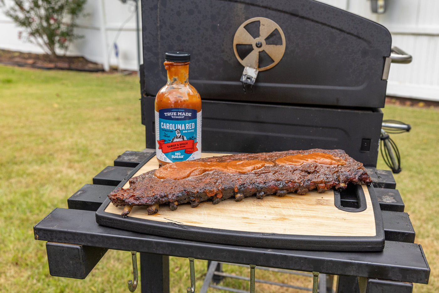 Barbecued ribs on the grill with True Made Foods Carolina Red tangy & spicy no sugar sauce. 