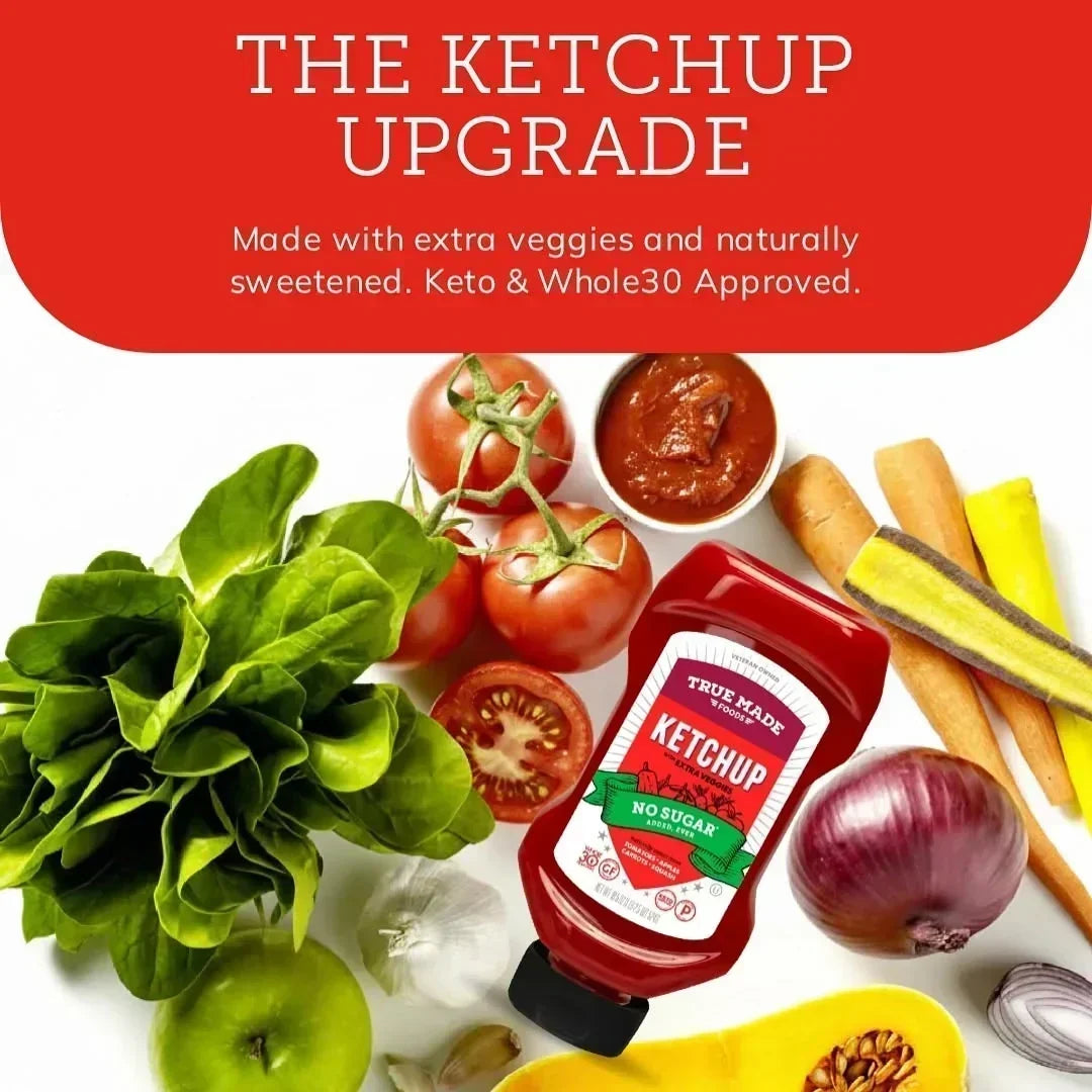 A bottle of True Made Foods ketchup surrounded by fresh vegetables like tomatoes, lettuce, carrots, and an apple.