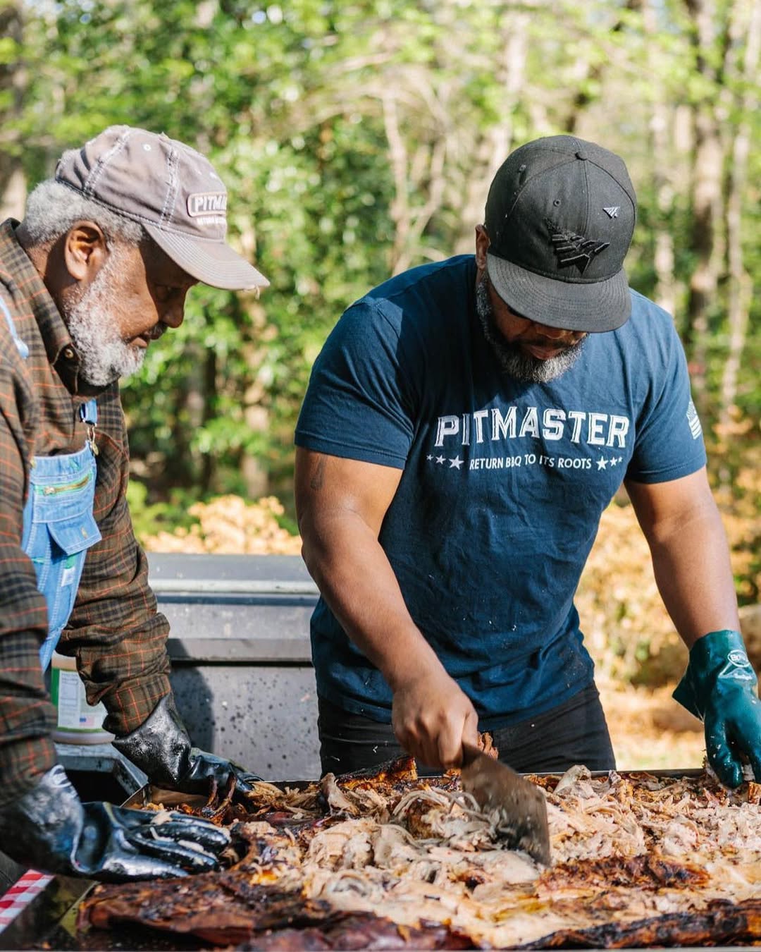 Two pitmasters preparing barbecued meat outdoors using True Made Foods BBQ sauces.
