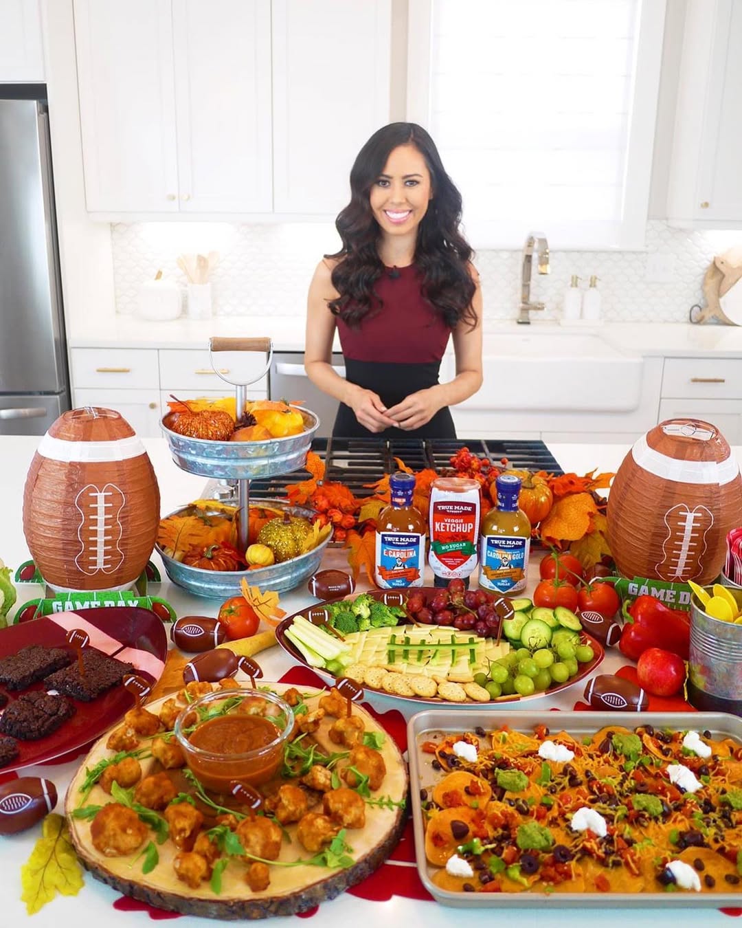 A host presenting snack boards with vegetables, dips, proteins, and True Made Foods sauces.