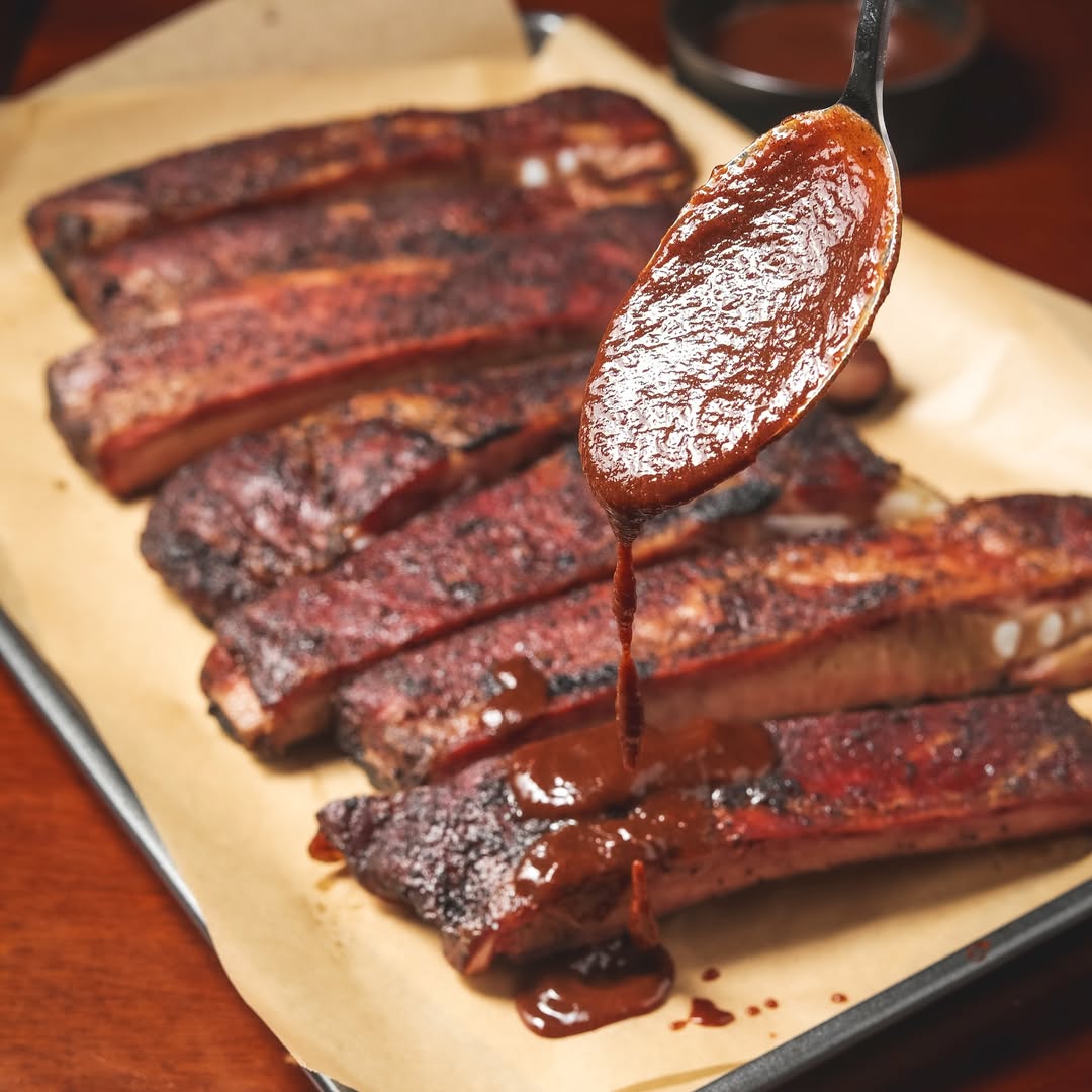 BBQ ribs with True Made Foods BBQ sauce being drizzled on top from a spoon.