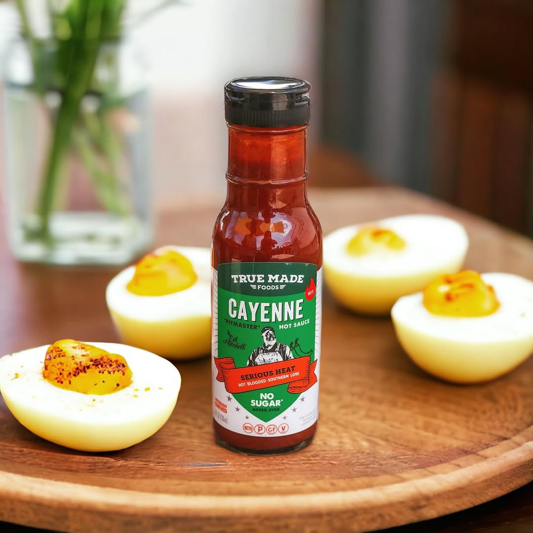 True Made Foods Cayenne Hot Sauce on a tray, boiled eggs behind, ready for a protein-packed spicy bite.